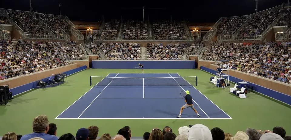 Tennis match in front of a large night crowd