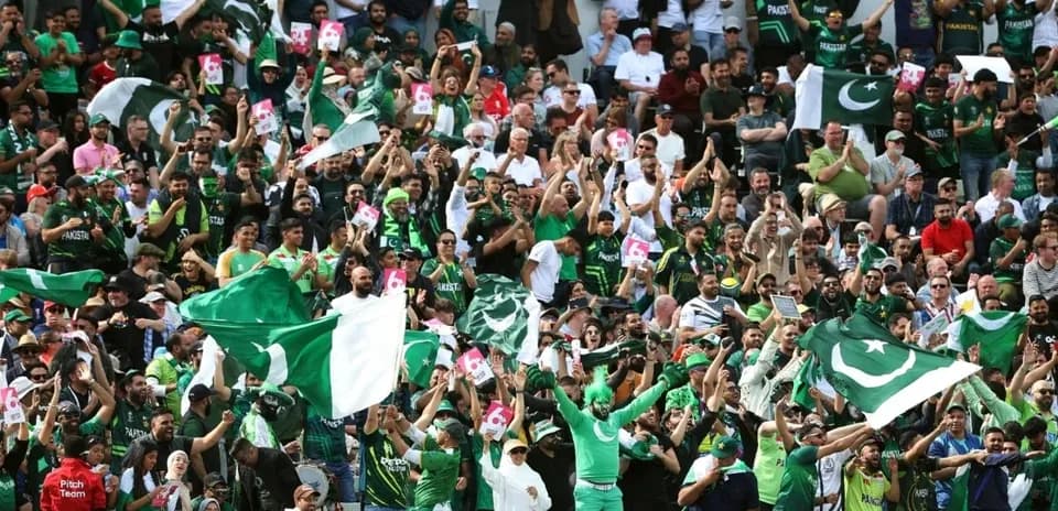 Crowd of fans waving Pakistan flags at match