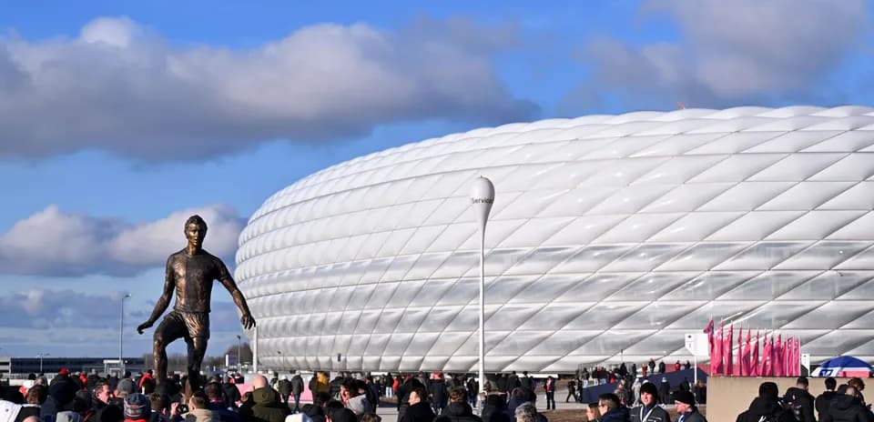 Crowd near stadium with statue in foreground