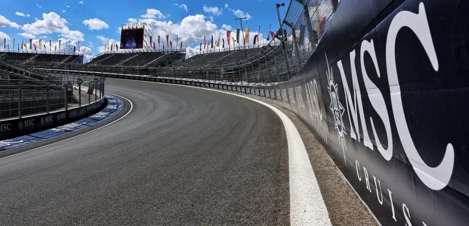 Curved racetrack with grandstands and blue sky