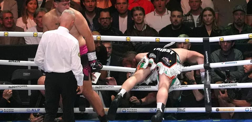 Boxer knocked down against the ropes in the ring