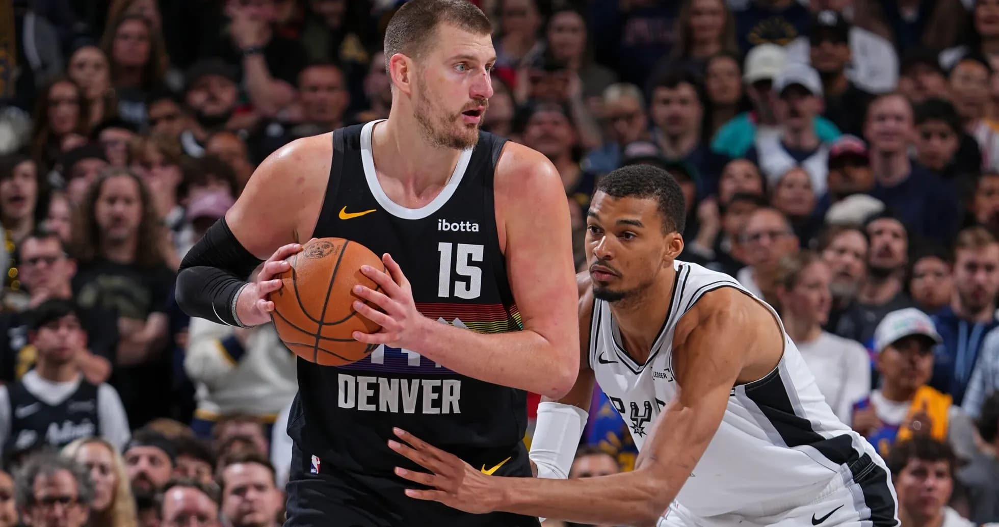 Player dribbling basketball while defended by opponent