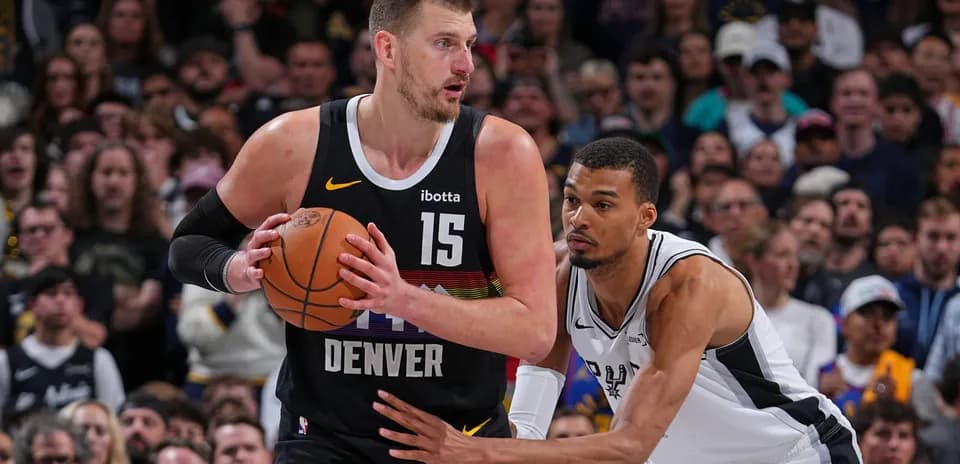 Player dribbling basketball while defended by opponent