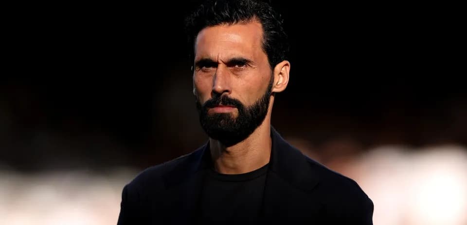 Man with beard and dark attire looking serious