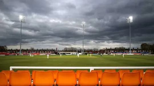 Cricket match in progress under cloudy skies