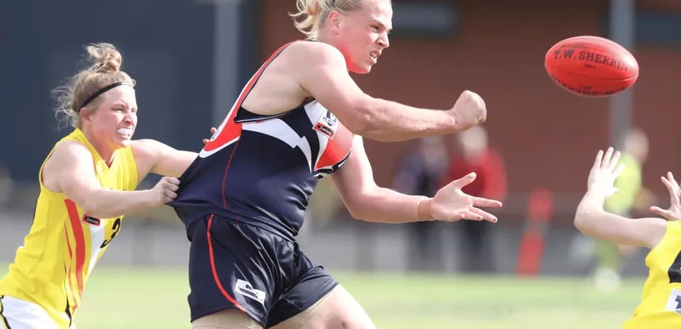 Player passing the ball while being tackled in match
