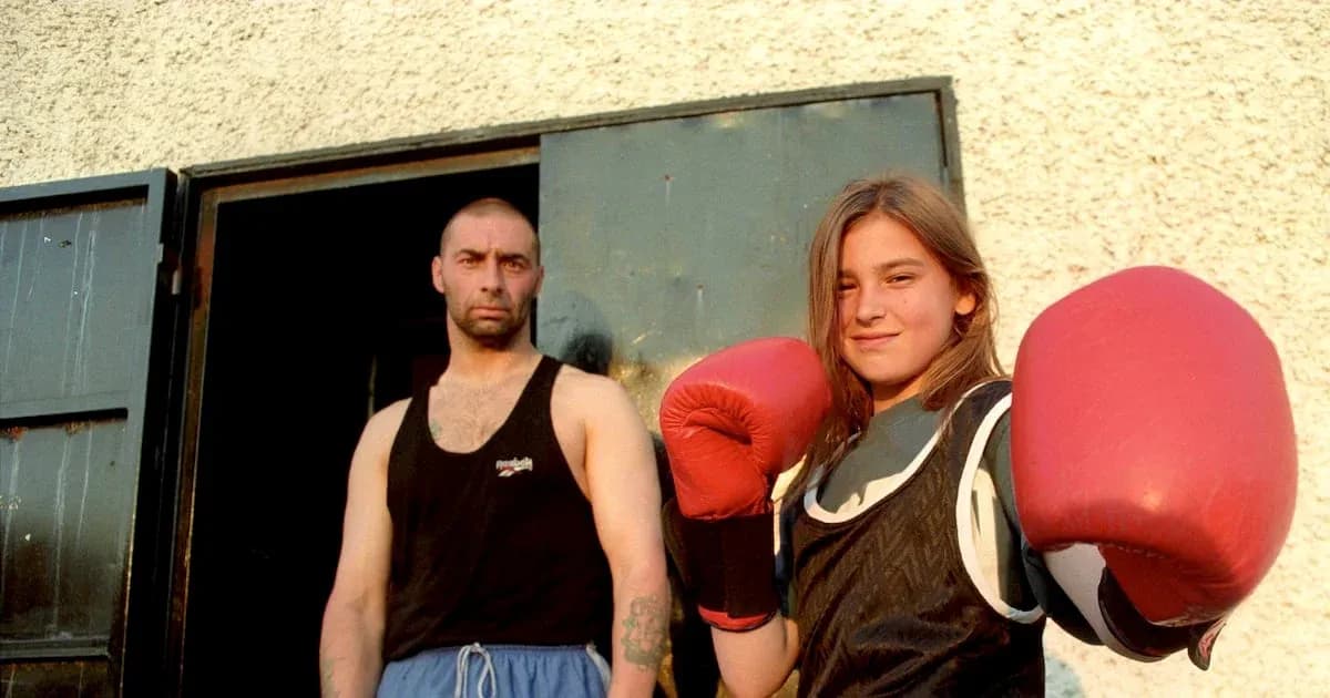 Young female boxer posing with trainer outside gym