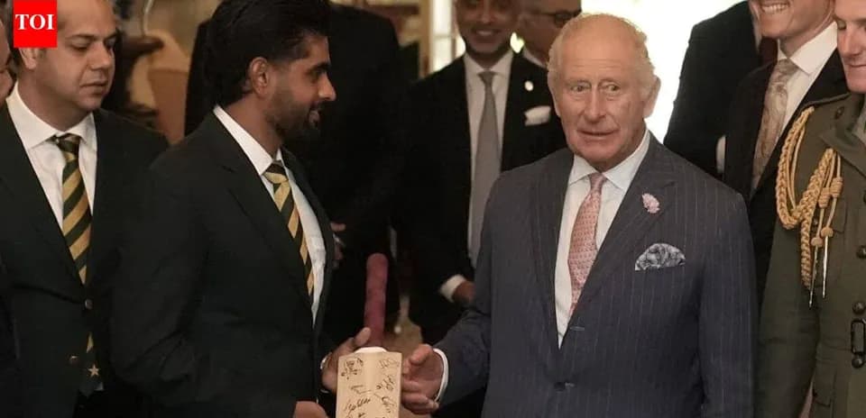 Cricket team members presenting signed bat to Charles