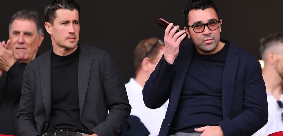 Two men seated in a sports venue watching event