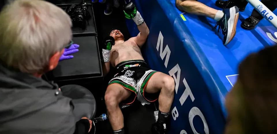 Boxer on the ground after a match, surrounded by team