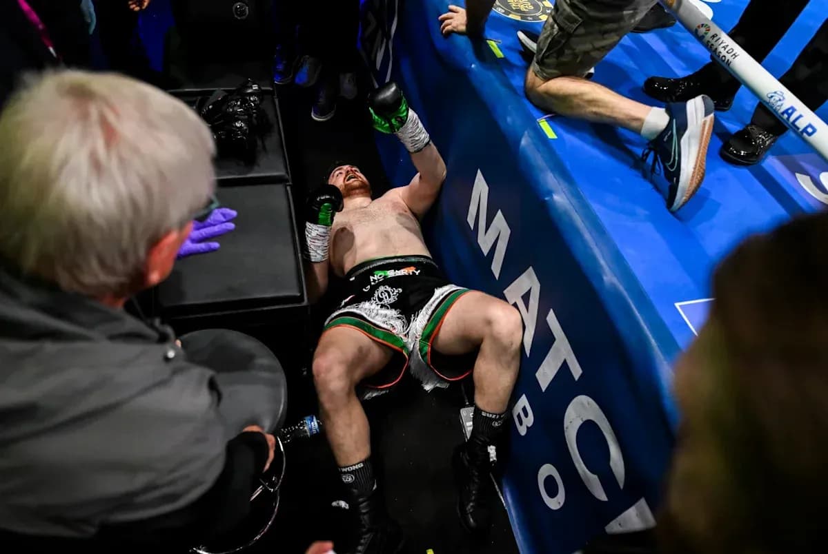Boxer on the ground after a match, surrounded by team