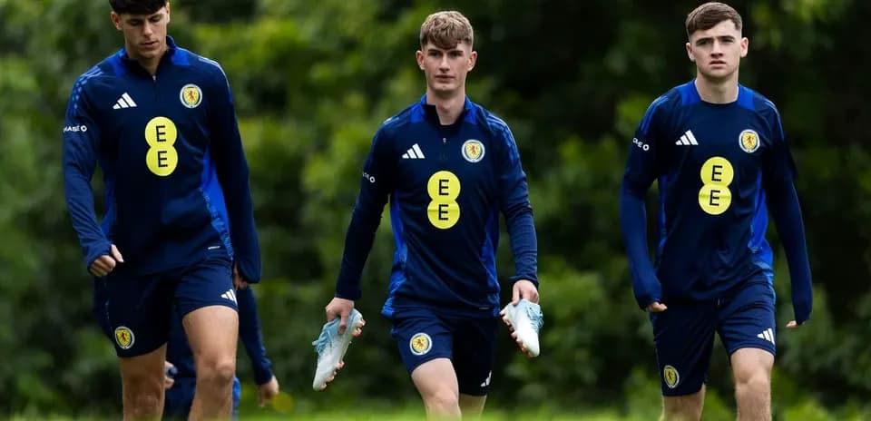 Three players walking in training gear on pitch