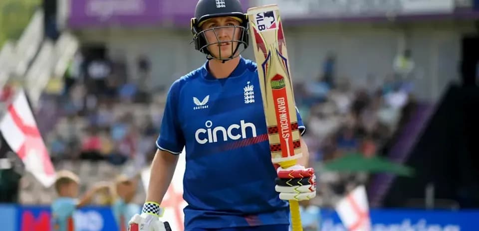 Cricketer in blue uniform walking with bat