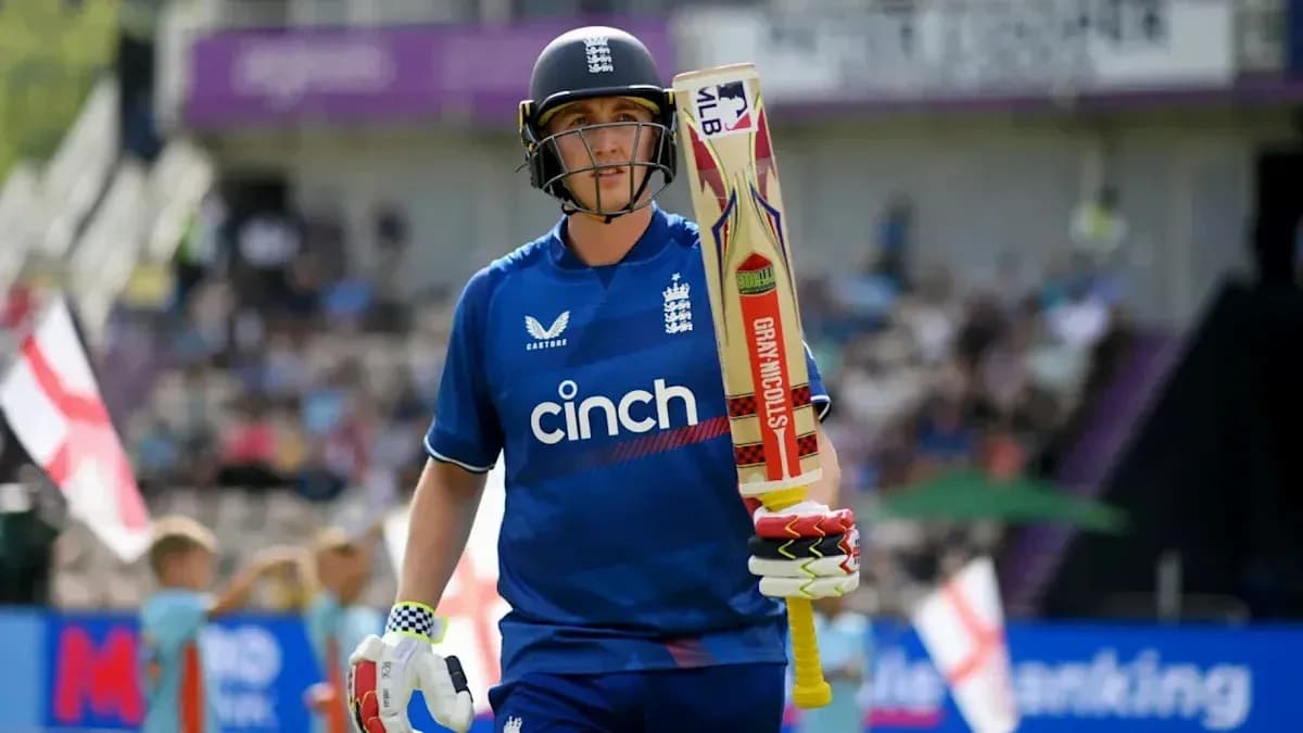 Cricketer in blue uniform walking with bat