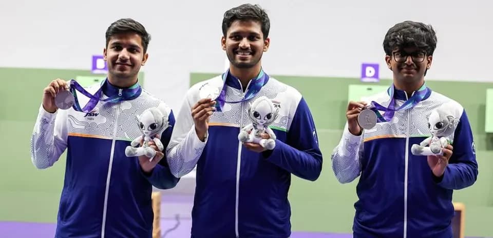 Three athletes holding medals and mascots at event