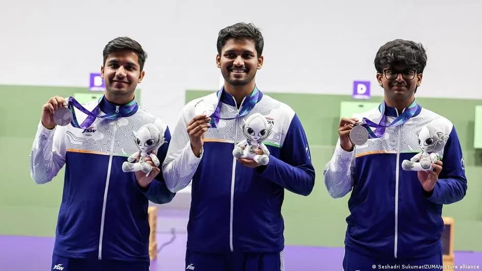 Three athletes holding medals and mascots at event