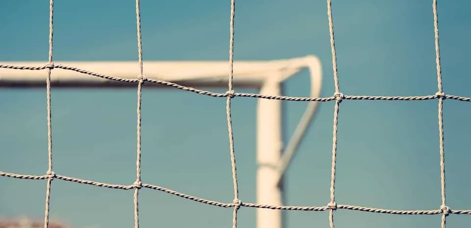 Close-up of a soccer goal net with blue sky