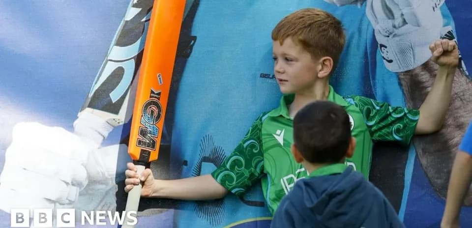 Child posing with a cricket bat in front of poster