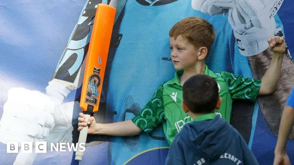 Child posing with a cricket bat in front of poster