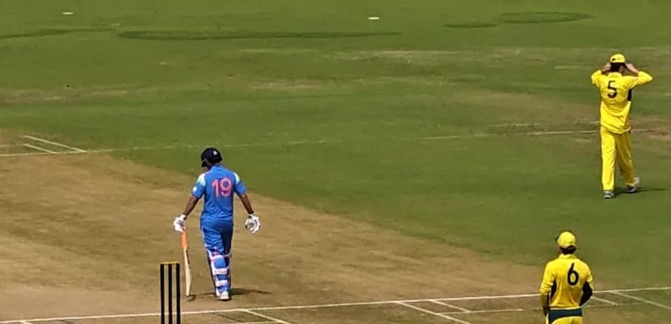Batsman in blue uniform walking towards crease