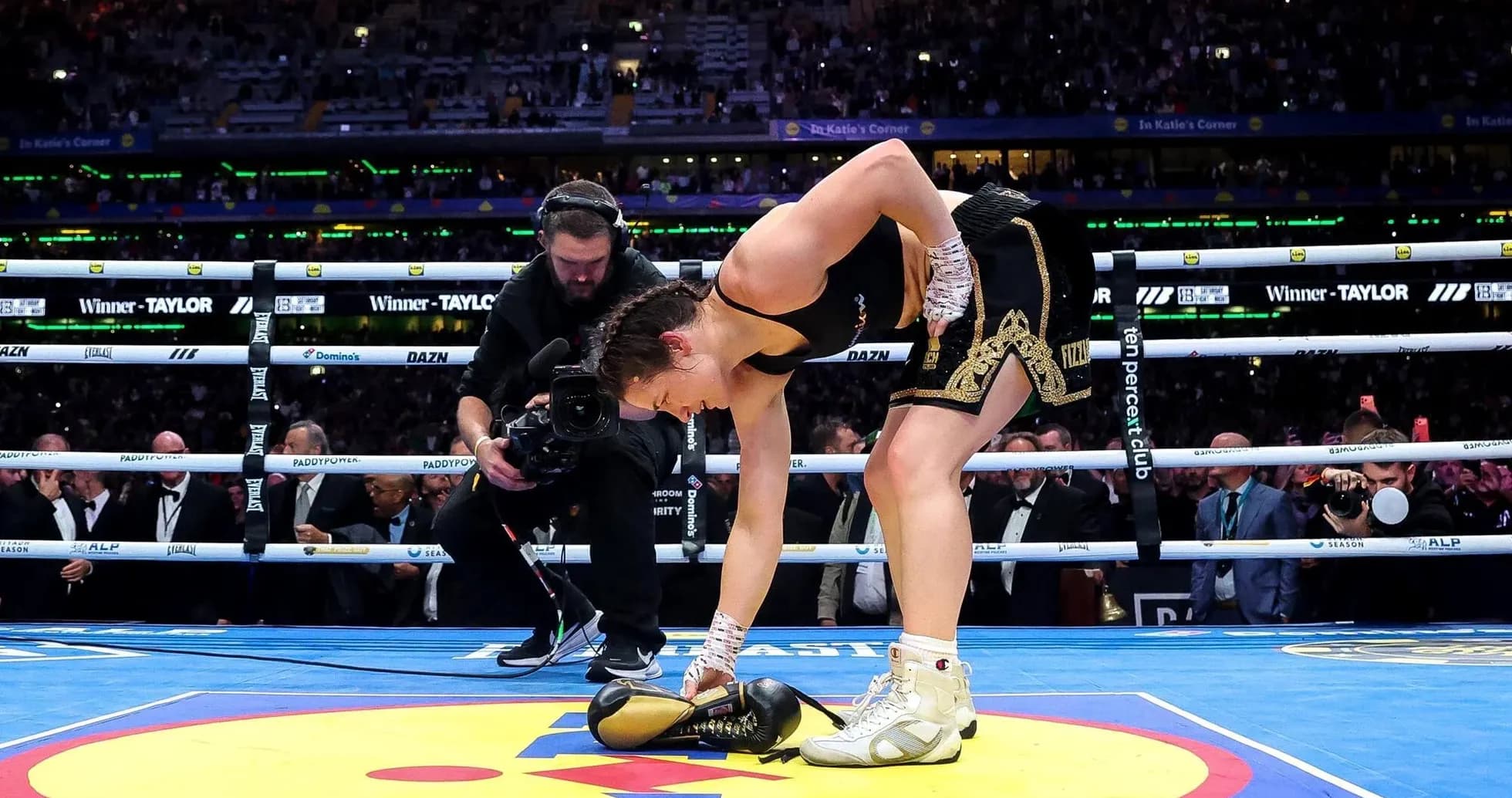 Female boxer picking up gloves in the ring