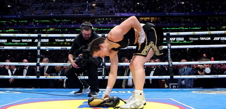 Female boxer picking up gloves in the ring