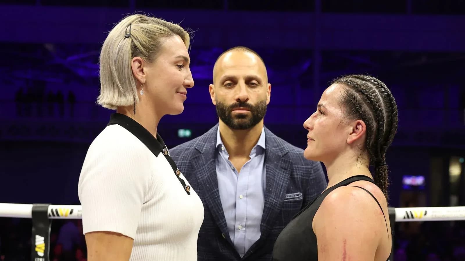 Two fighters facing off with a referee in between