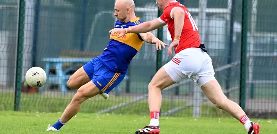 Player kicking a ball while being challenged by opponent