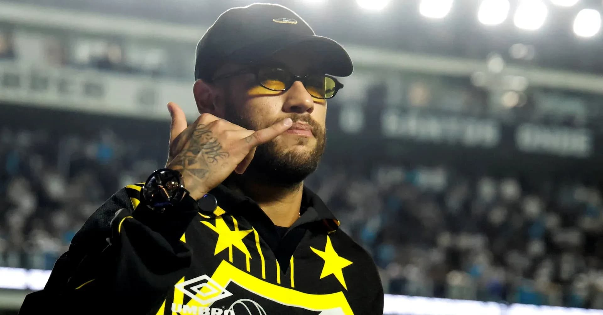 Person making a phone gesture in stadium
