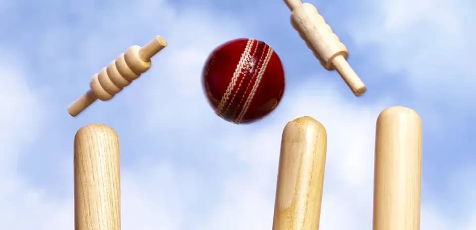 Cricket ball hitting stumps with bails flying
