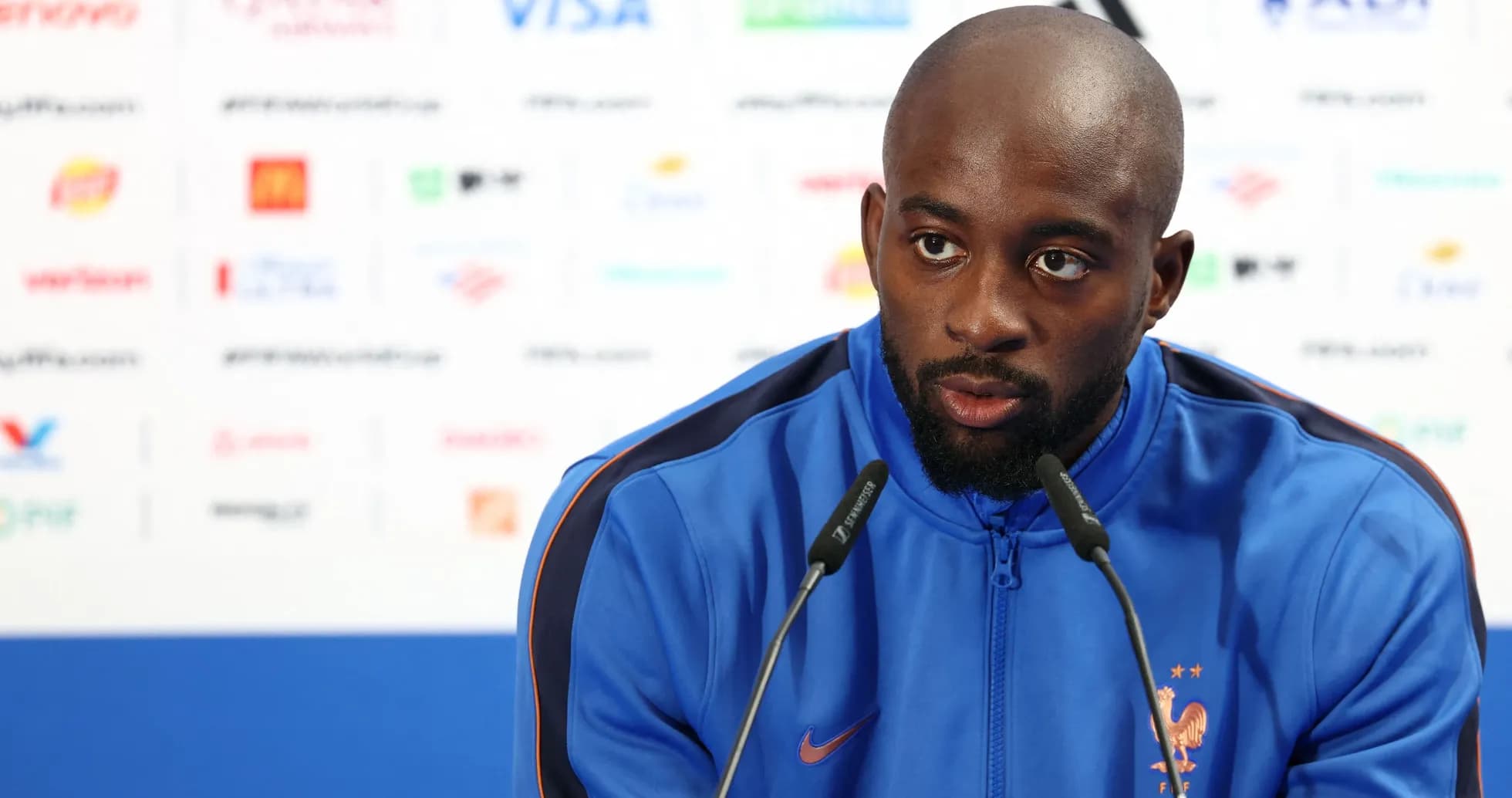 Player speaking at a press conference with microphones