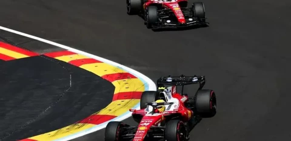 Two Ferrari cars racing around a corner