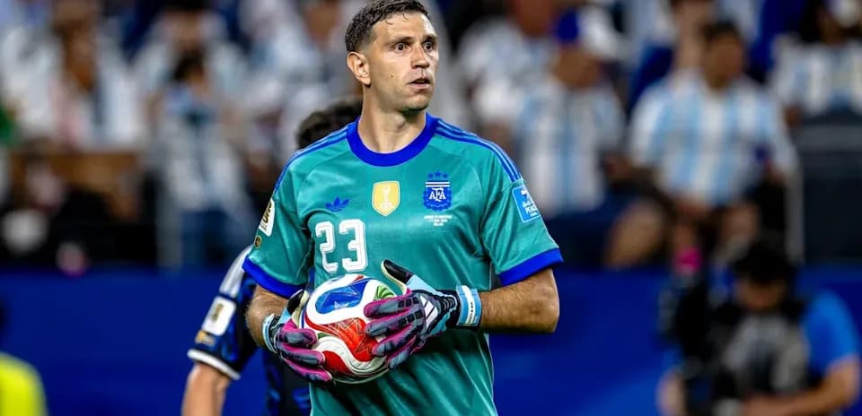 Goalkeeper in teal jersey holding soccer ball