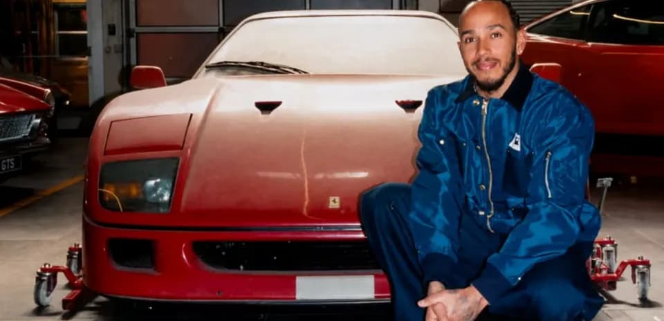 Man kneeling beside a vintage red Ferrari in garage