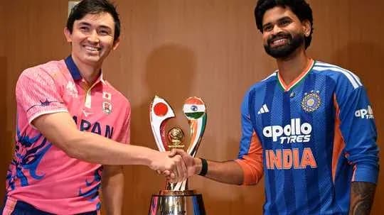 Players from Japan and India shaking hands over trophy