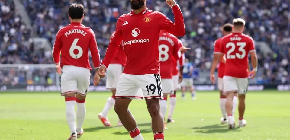 Player celebrating on the pitch with teammates behind