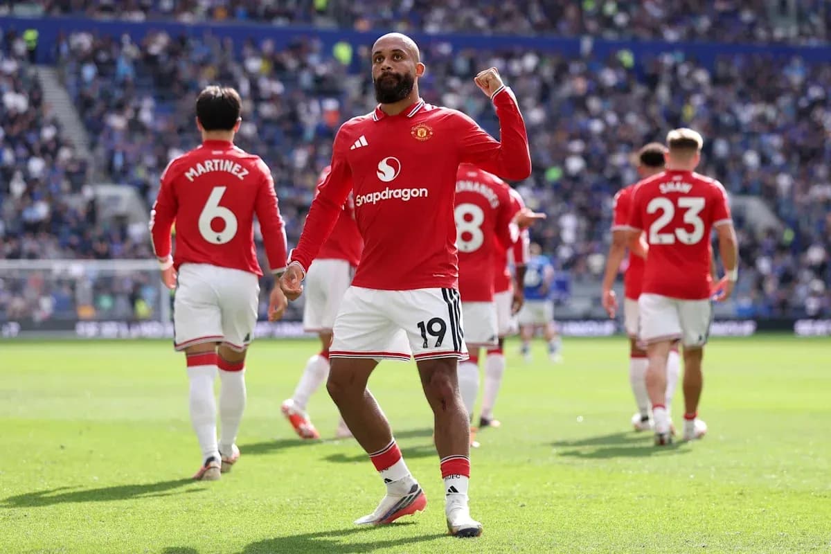 Player celebrating on the pitch with teammates behind