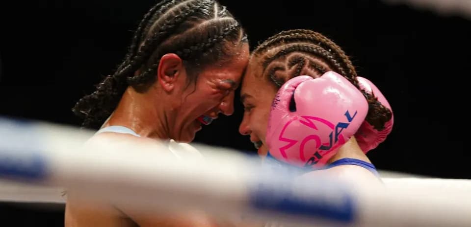 Two female boxers in close embrace during match