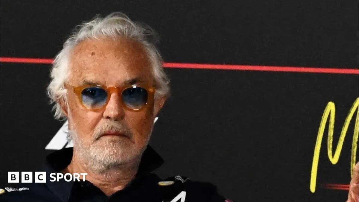 Man with glasses at a press conference backdrop