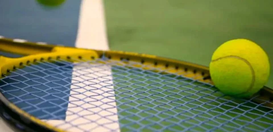 Tennis ball resting on racket near court lines