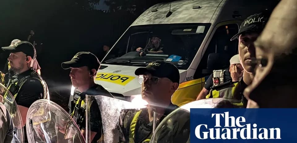 Police officers with shields and van at night
