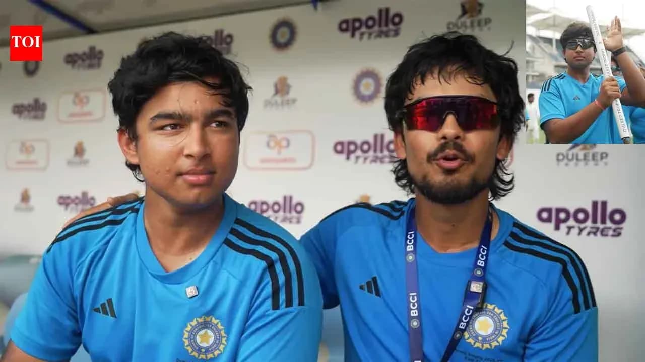 Two young cricketers in blue jerseys at press conference