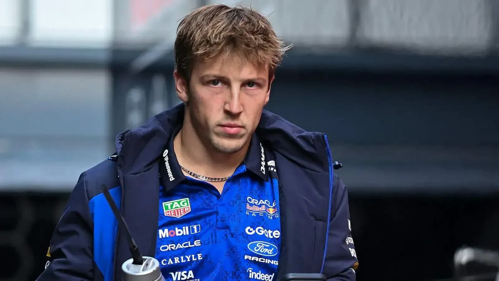 Driver in team jacket holding a drink bottle