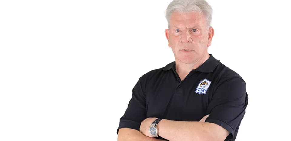 Coach with arms crossed, wearing a black polo shirt