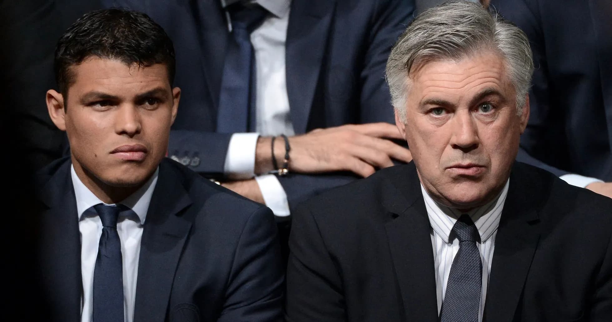 Two men in suits sitting together at event