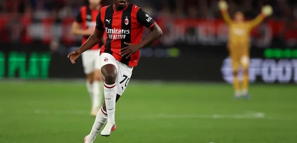 Player in AC Milan kit sprinting towards the ball