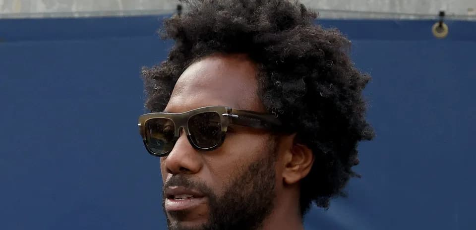 Person wearing sunglasses with curly hair
