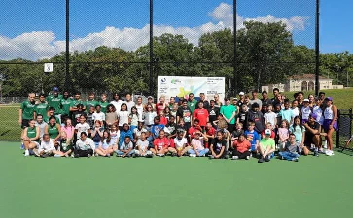 Group photo on tennis court with participants and coaches