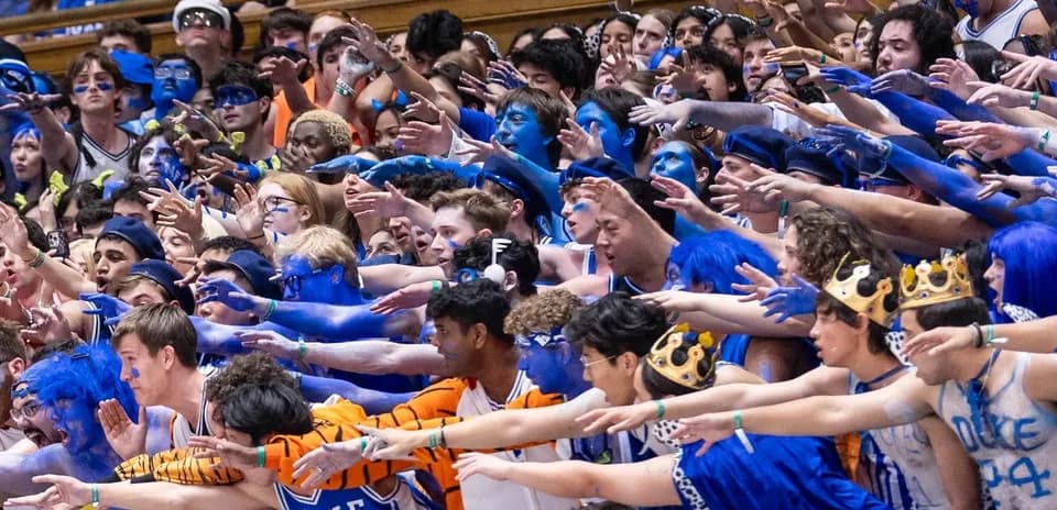 Duke fans cheering with blue face paint and costumes