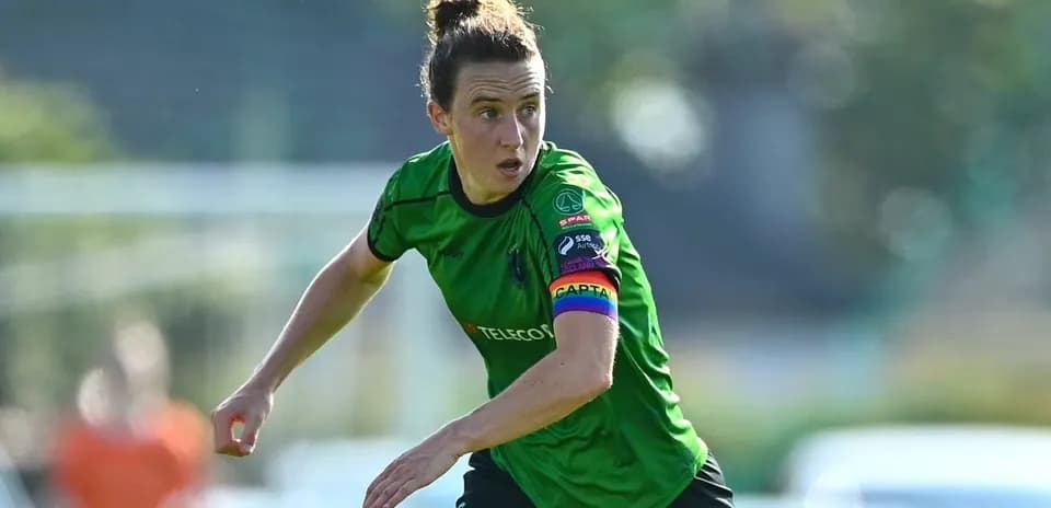 Player in green kit with captain's armband running
